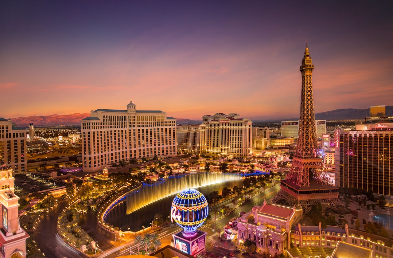 who-we-are Stunning aerial view of Las Vegas skyline at sunset, featuring the Eiffel Tower and Bellagio fountains.